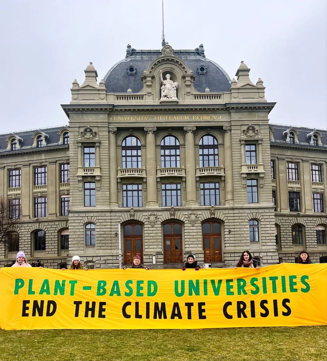 Students holding a Plant-Based Universities banner outside the University of Bern.